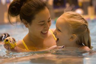 A student with a child in the pool
